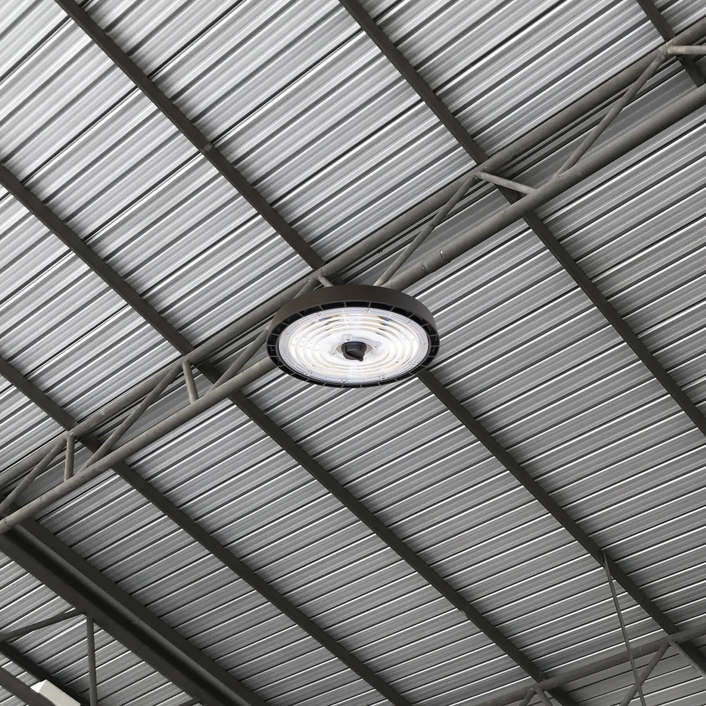 Luminaire circulaire de grande hauteur Perform Pro Max Integral LED installé sur un support métallique contre un plafond en tôle ondulée