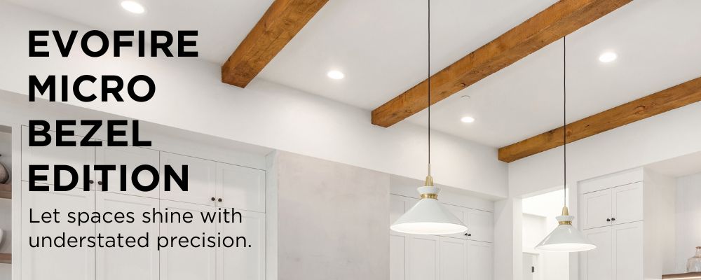 Modern white kitchen. Image focus on ceiling with wood beams and downlights. Text reads 'Evofire Micro Bezel Edition. Let spaces shine with understated precision.' 