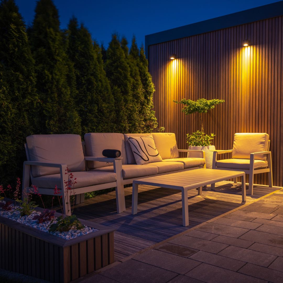 Outdoor living space with exterior wall of home in background lit by wall mounted LED light fixtures