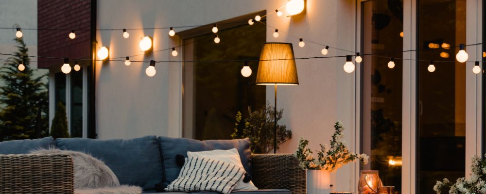 Exterior living space at dusk with warm white lighting - festoons and standing lamp